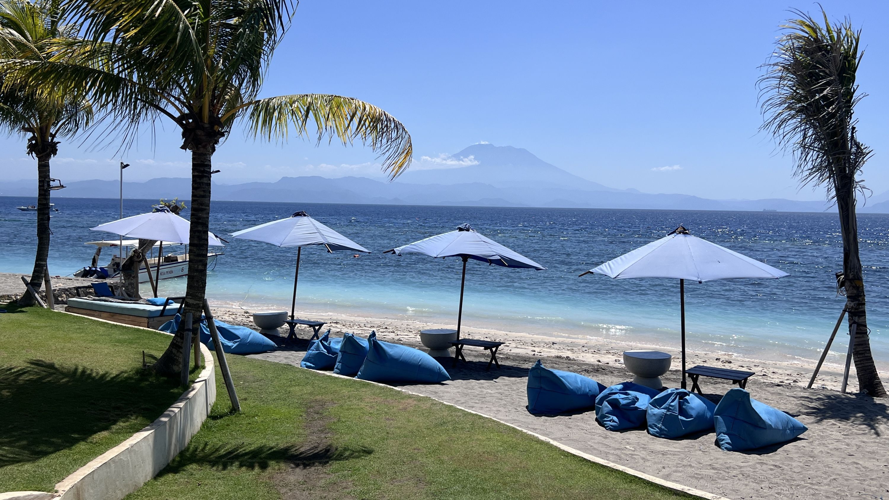 Sunbathers on the beach look out at Mount Agung